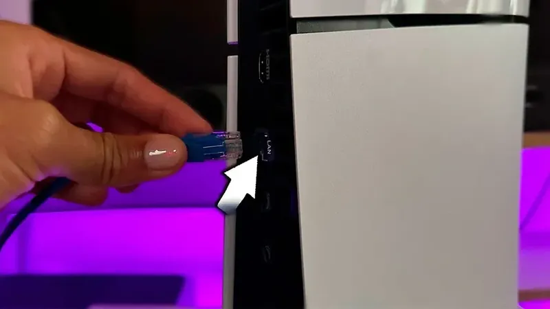 Cable de red LAN siendo conectado a la PS5 para mejorar conexión.