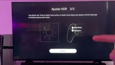 Pantalla PS5 mostrando el paso 3/3 del ajuste HDR con símbolo de brillo y mando DualSense en TV.