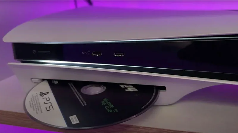 Consola PS5 con disco de juego 2K "Welcome to the Club" siendo insertado en la ranura lectora.