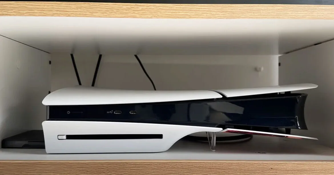 PS5 Slim horizontal en estante de madera con poco espacio, mostrando ranura de disco y puertos USB frontales.