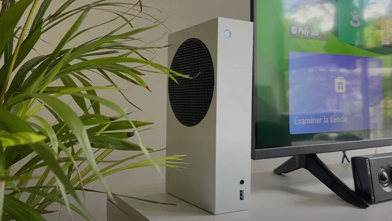 Xbox Series S en blanco junto a televisor con interfaz Xbox y texto "Examinar la tienda