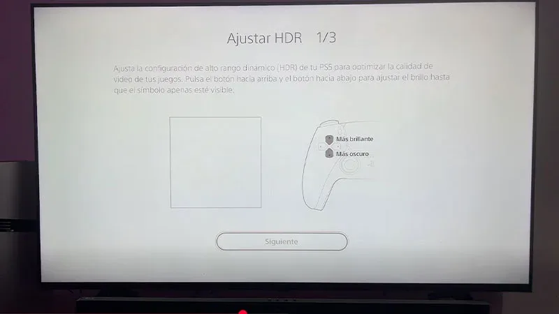 Pantalla de ajuste HDR en PS5 con mando DualSense, paso 1 de 3, opciones más brillante y más oscuro.